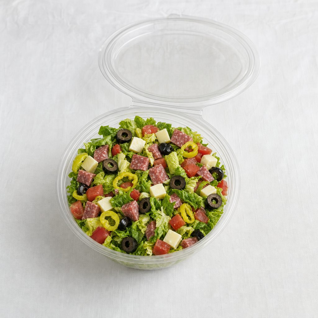 Italian chopped salad in a clear round hinged container on a white tablecloth