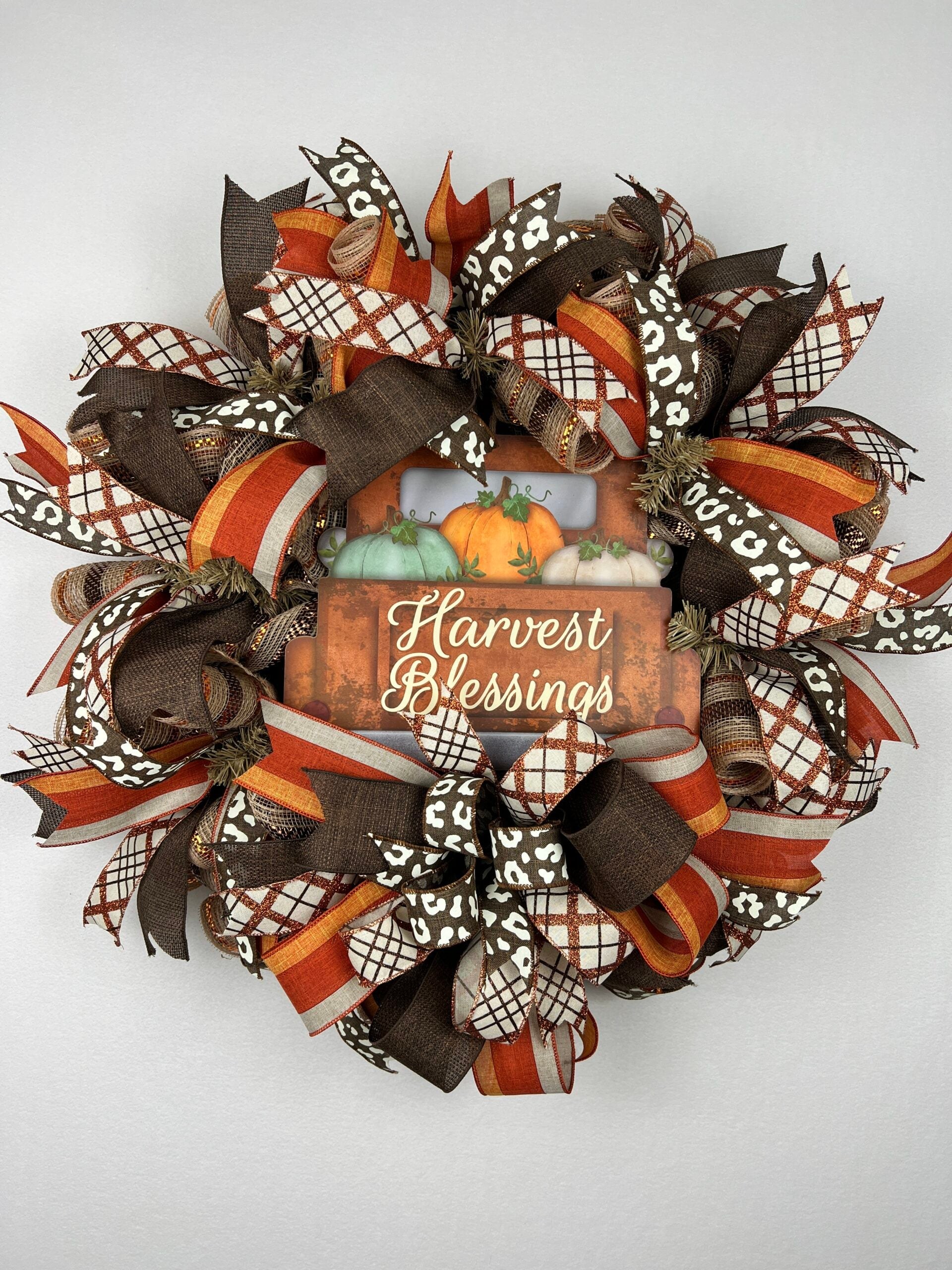 Handmade fall harvest wreath with layered ribbon and pumpkins