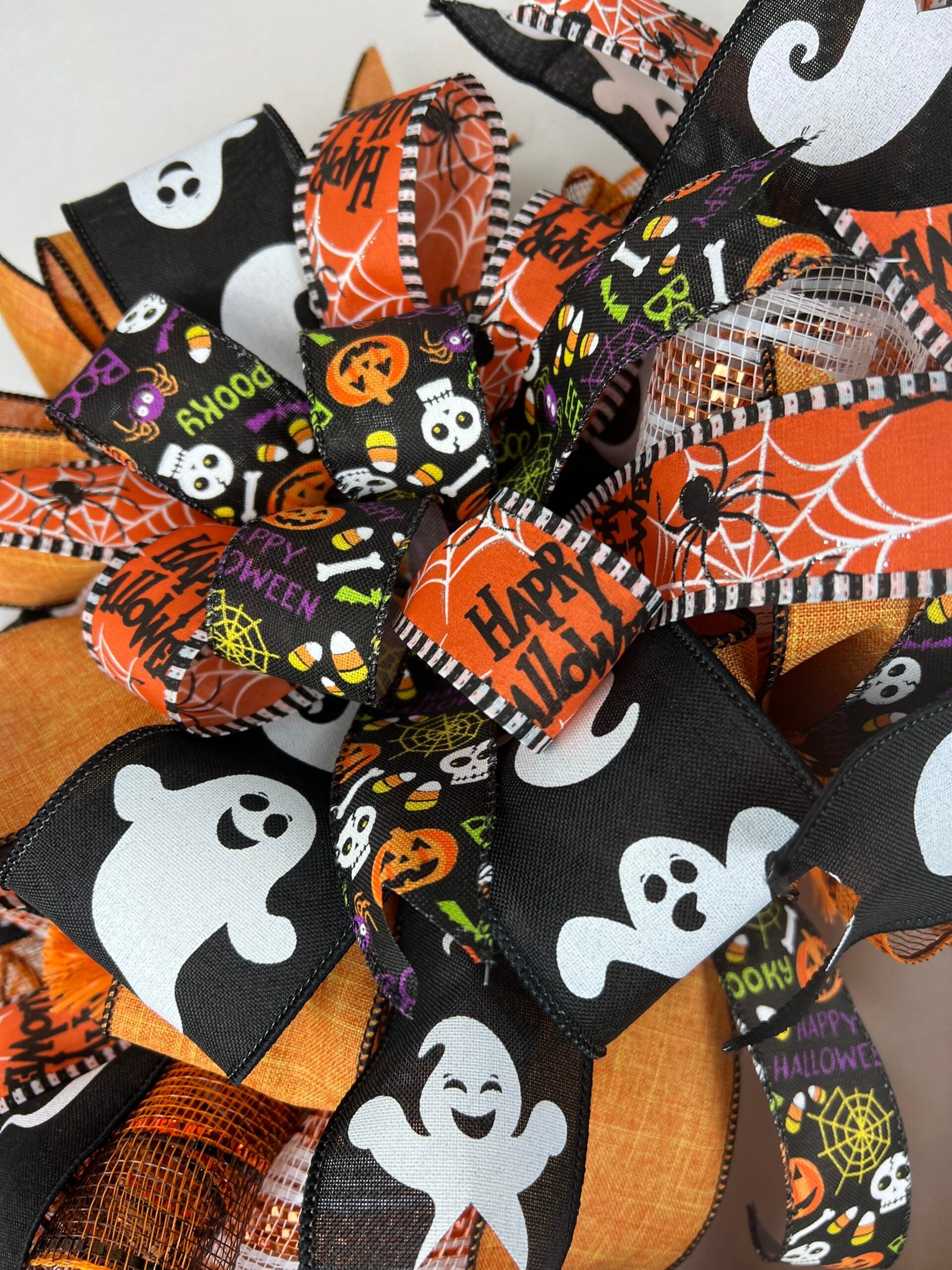 Finished Halloween deco mesh wreath with orange, black, and patterned ribbon around a central sign