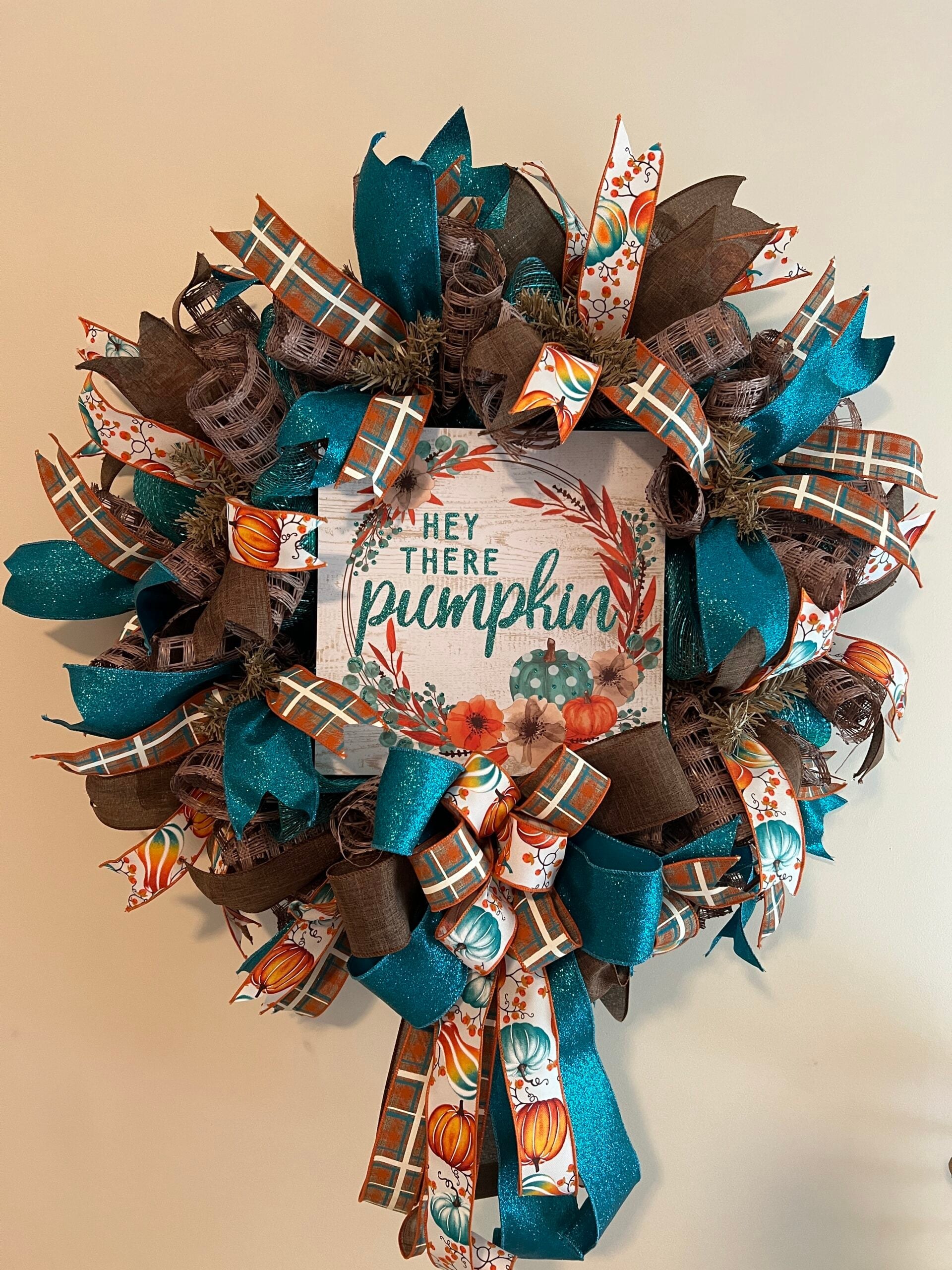 Finished fall wreath with teal and orange pumpkin accents, plaid ribbon, and a long bow