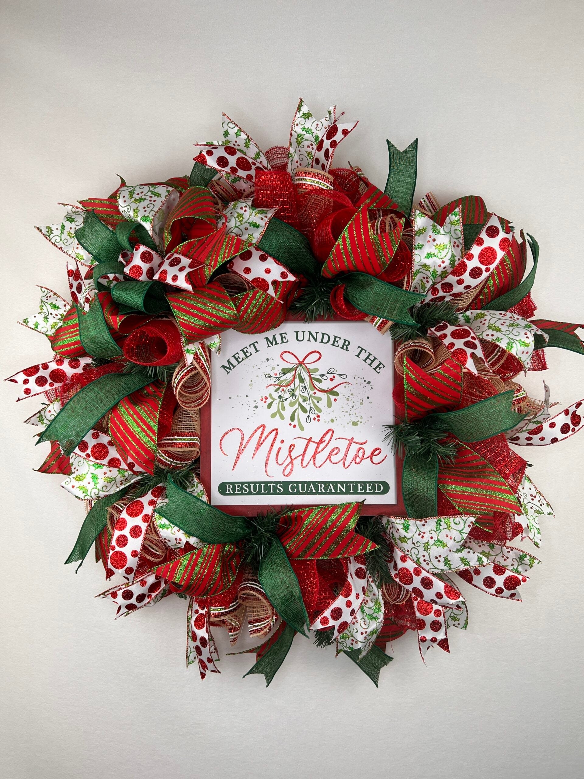Christmas deco mesh wreath with red, green, and white ribbons around a mistletoe sign