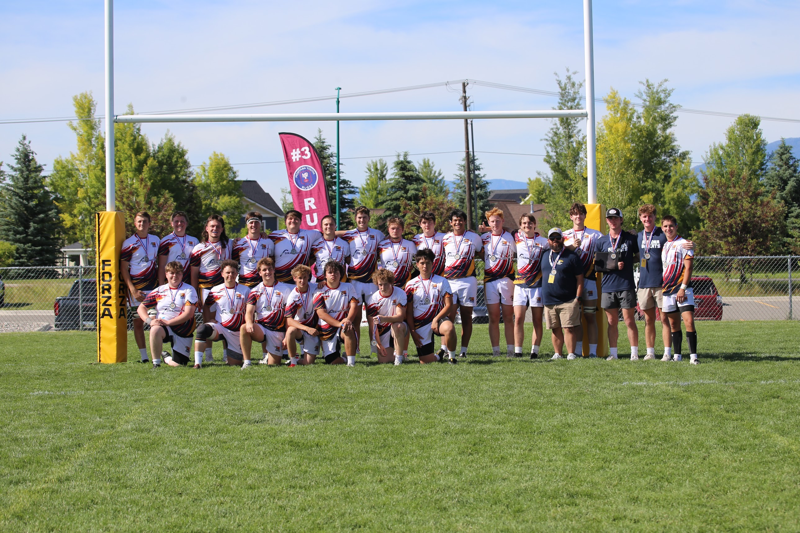 Bobcats rugby players and coaches with their medals beneath the goalposts