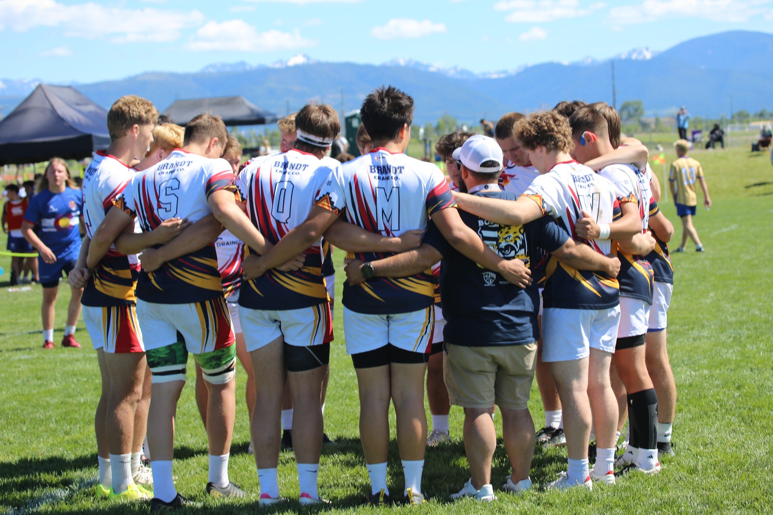 Bobcats rugby players and coaches gathered in a team huddle