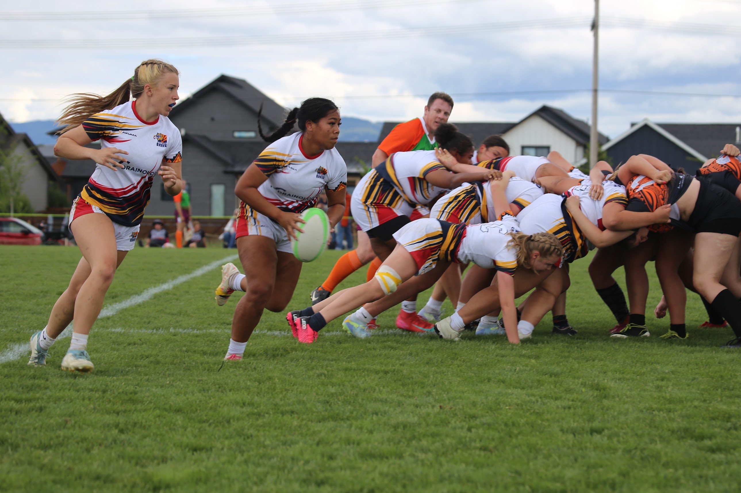 Bobcats girls playing rugby, with a ball carrier moving away from the scrum