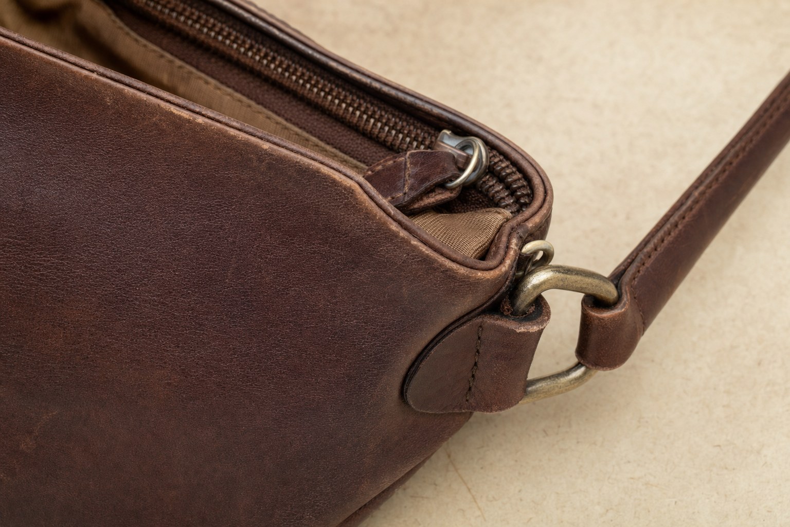 Close view of an anonymous vintage bag's strap attachment, zipper, and lining edge