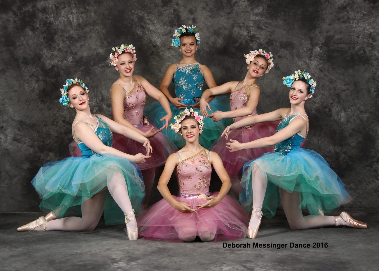 Ballet dancers posing together in teal and pink costumes