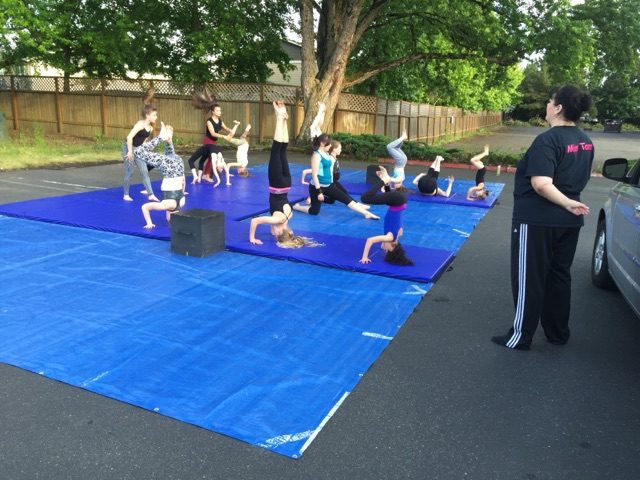 Children practising tumbling together on outdoor mats