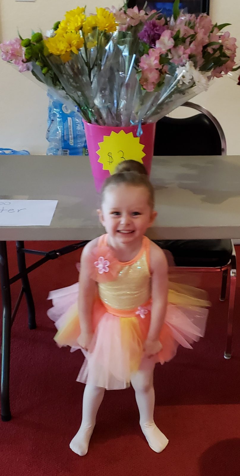 A smiling young dancer in a pastel rainbow costume