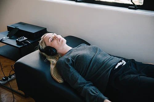 A person resting on an inHarmony Sound Lounge with headphones