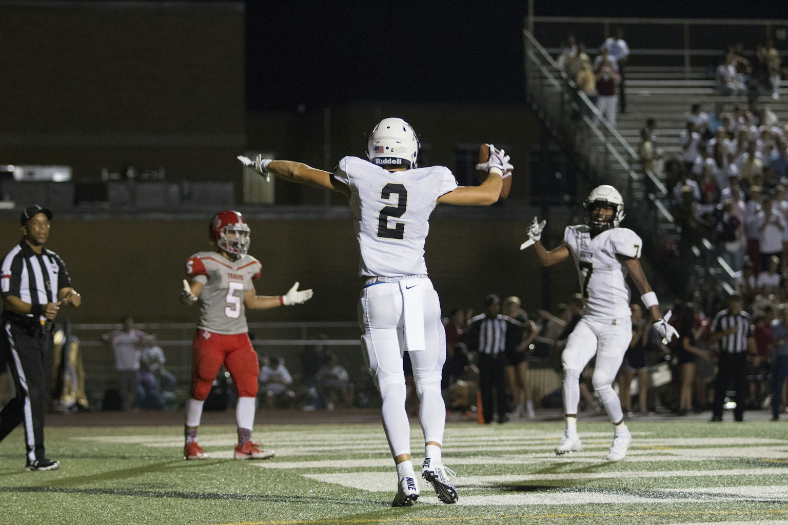 Football players celebrating a winning touchdown under stadium lights