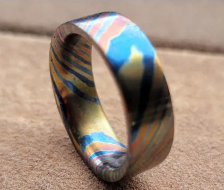Handmade flame-anodized titanium Damascus ring with a blue and bronze pattern
