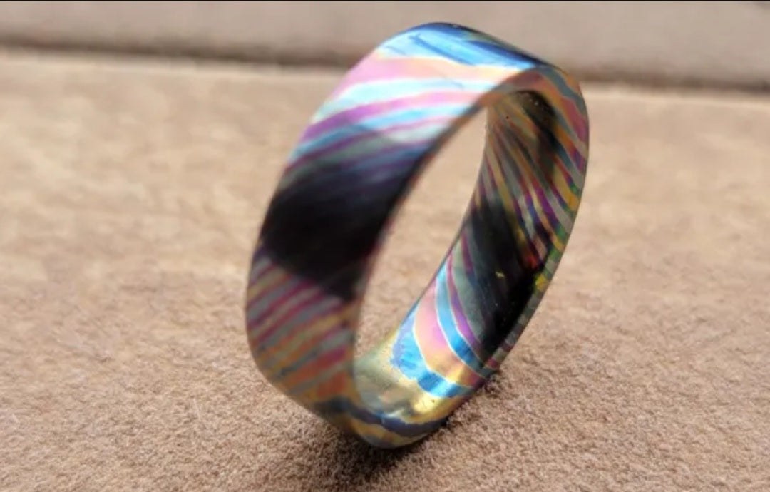 Close view of a blue, bronze, and violet flame-anodized titanium Damascus ring