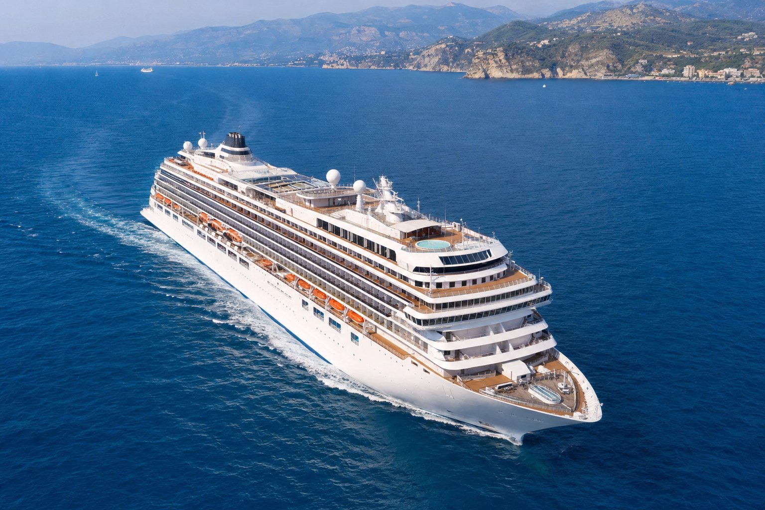 A modern cruise ship sailing in clear blue water, viewed from above.