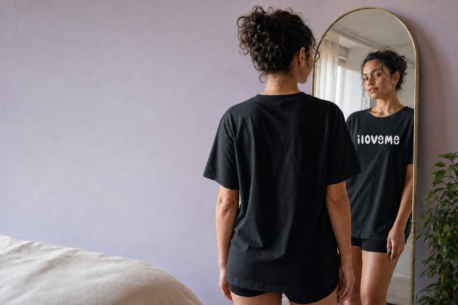 Woman with a blank-back T-shirt, seen from the front in a mirror wearing the emevoli design