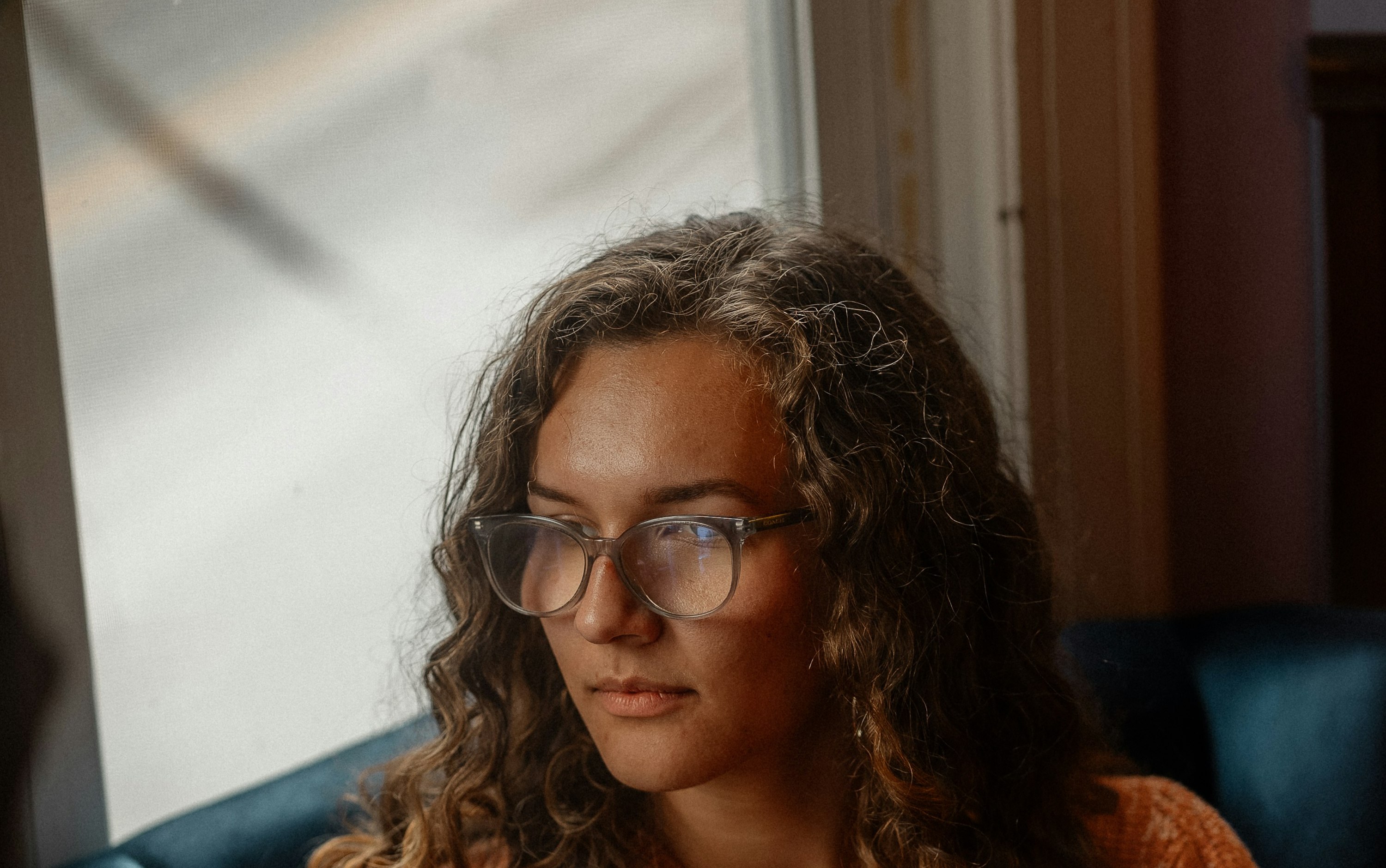 A woman sitting quietly in a chair near a window.