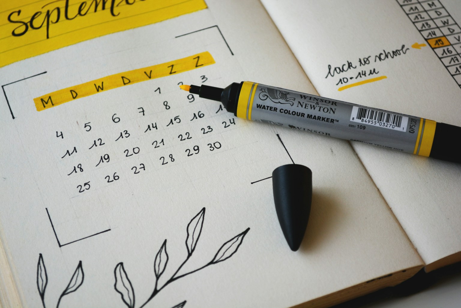 An open paper planner with handwritten notes and a pen.