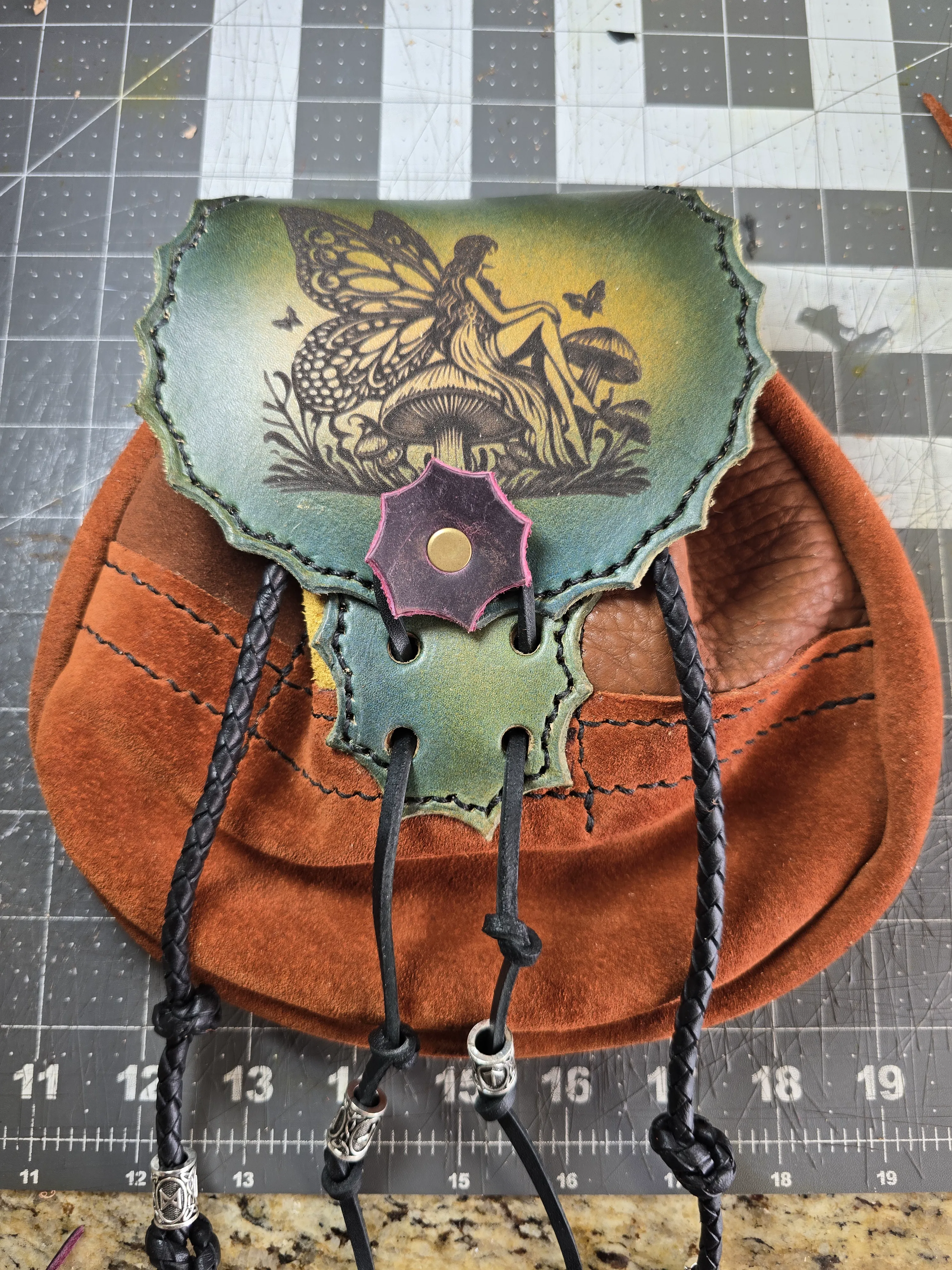 Close view of the Fae-Stitch Satchel's engraved leather flap and drawstring closure