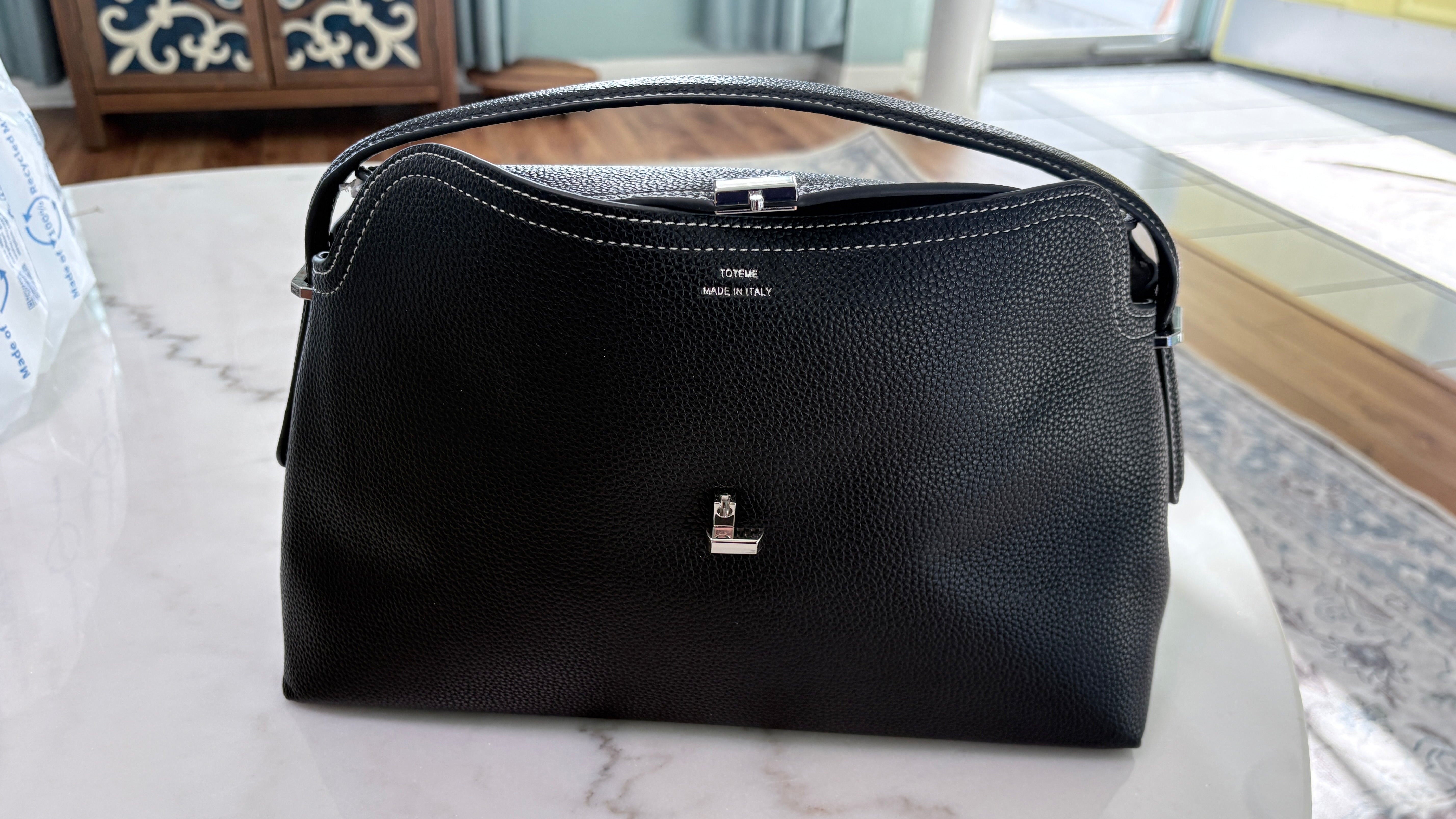 Black leather satchel showing its grained leather and silver-toned hardware