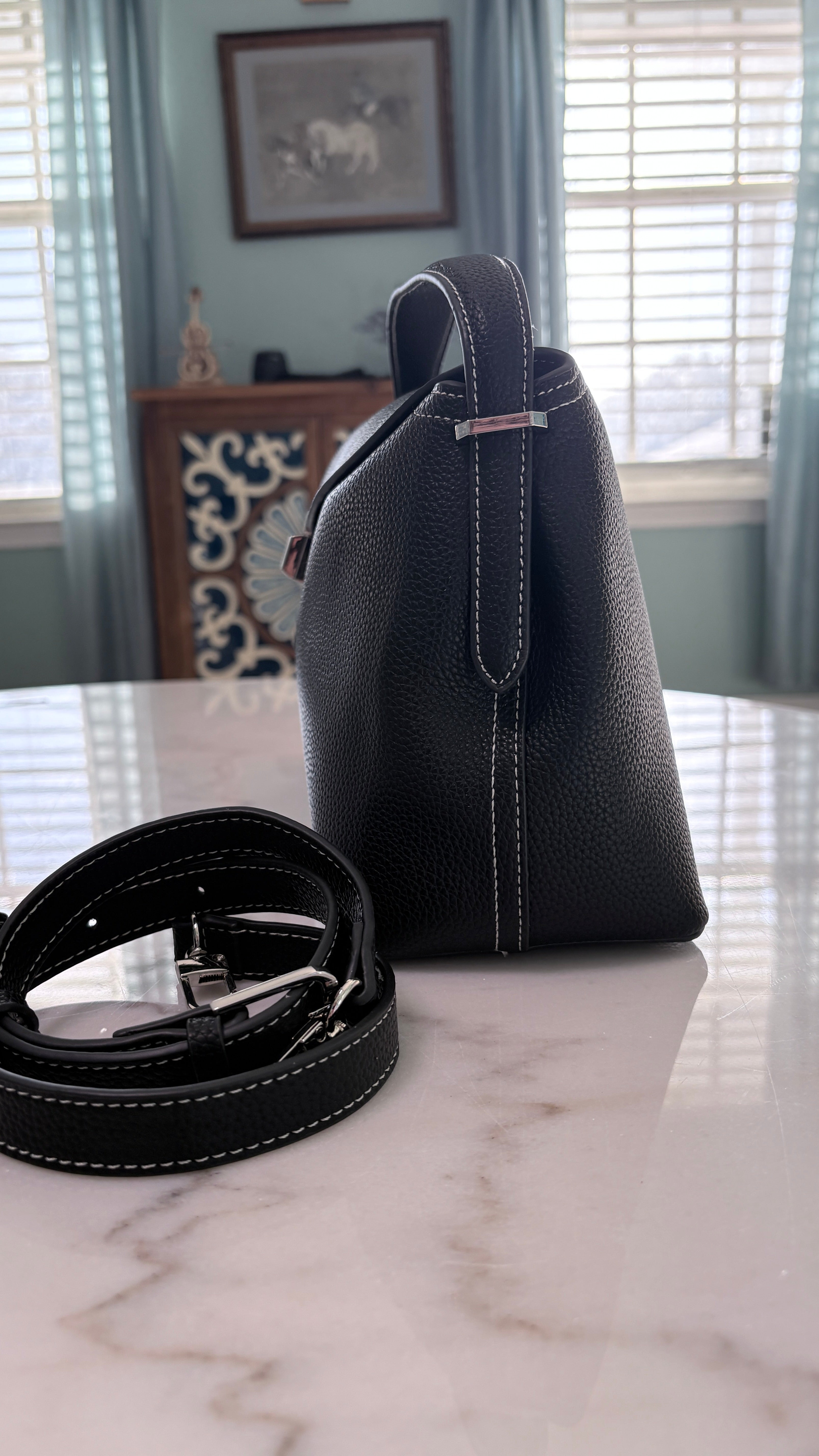 Black leather satchel showing its grained leather and contrasting stitching