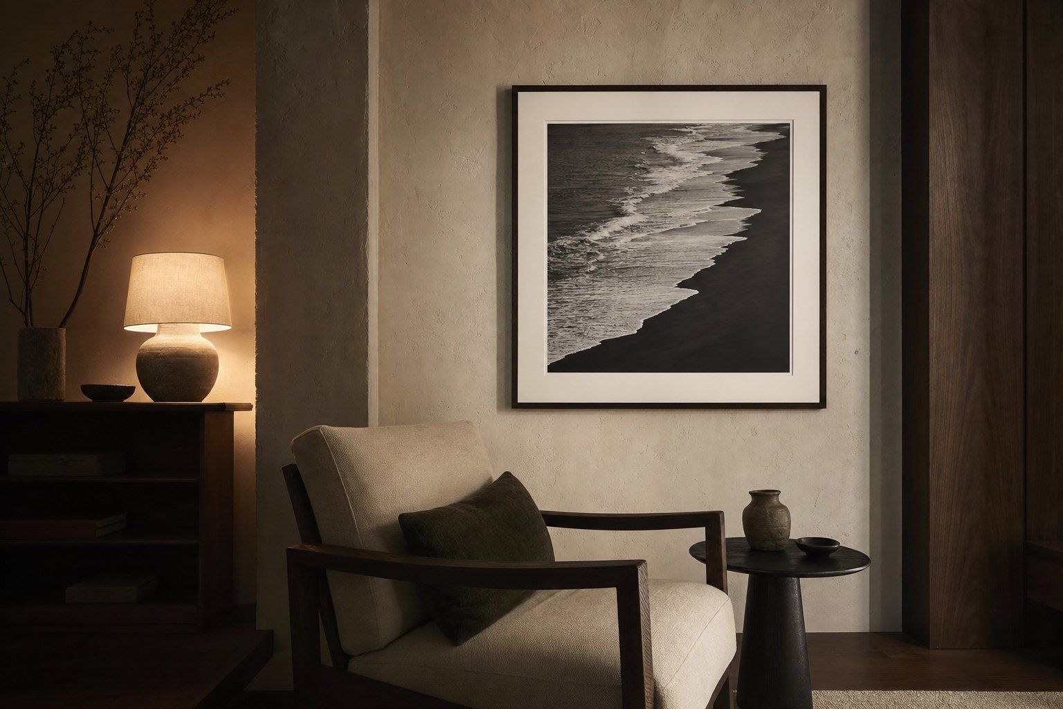 A black-and-white shoreline photograph above a chair in a warm, quiet reading corner.
