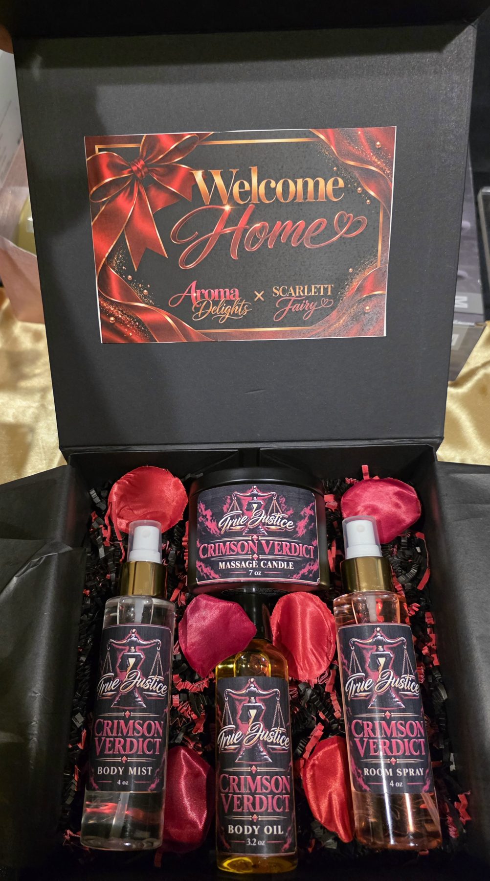 Open custom gift box with True Justice company branding on a massage candle, body mist, body oil and room spray