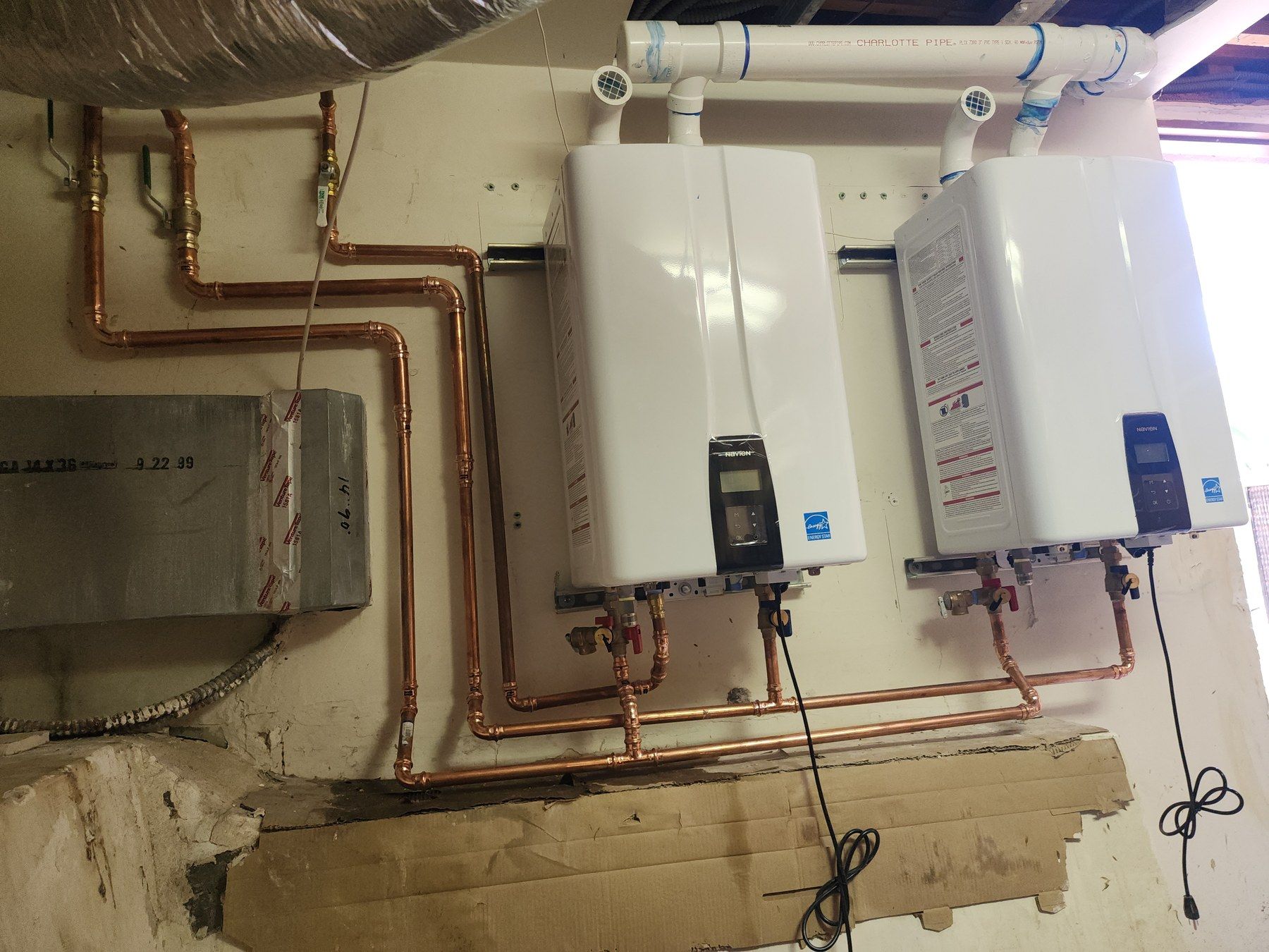 Two tankless water heaters with copper piping at a service location