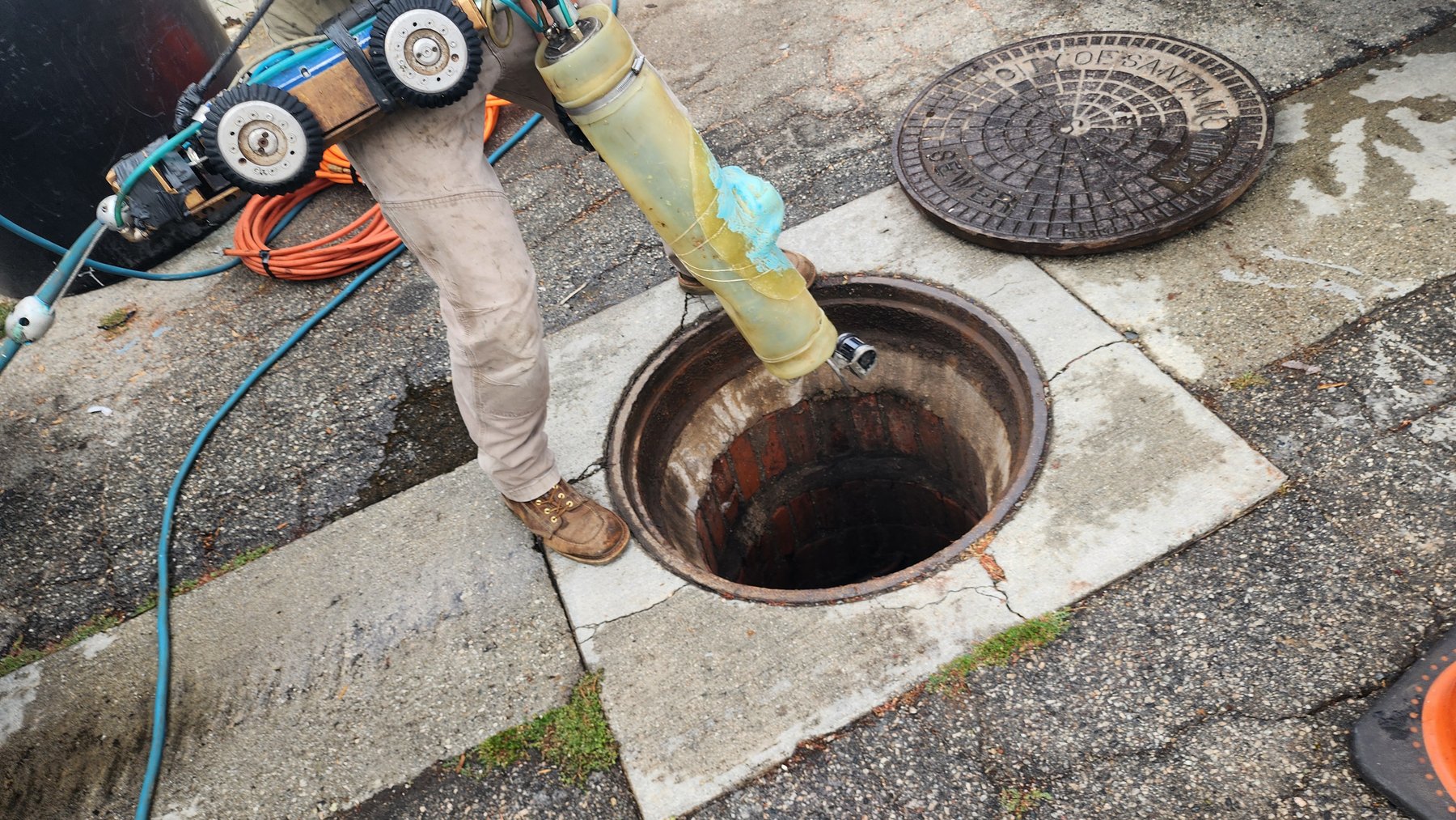 Technician operating sewer camera equipment at an exterior cleanout