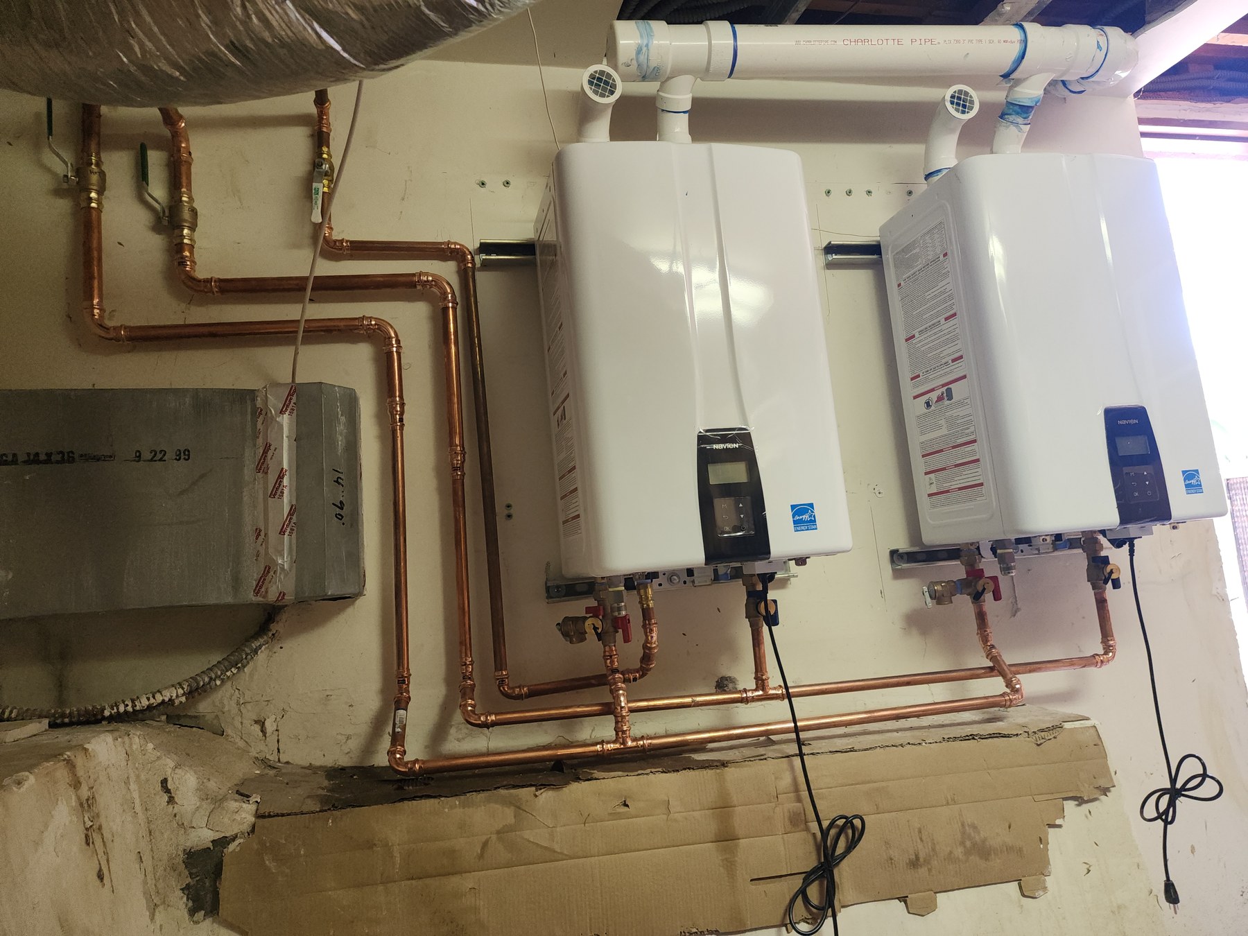 Two tankless water heaters with copper piping at a service location