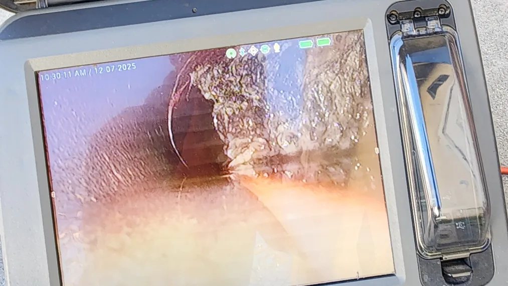Sewer inspection monitor showing actual footage from inside the pipe