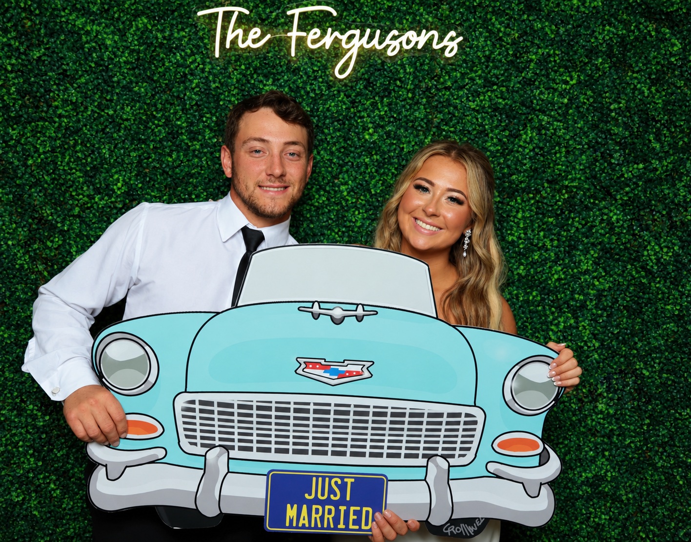 Couple posing with a vintage car photo prop at their wedding