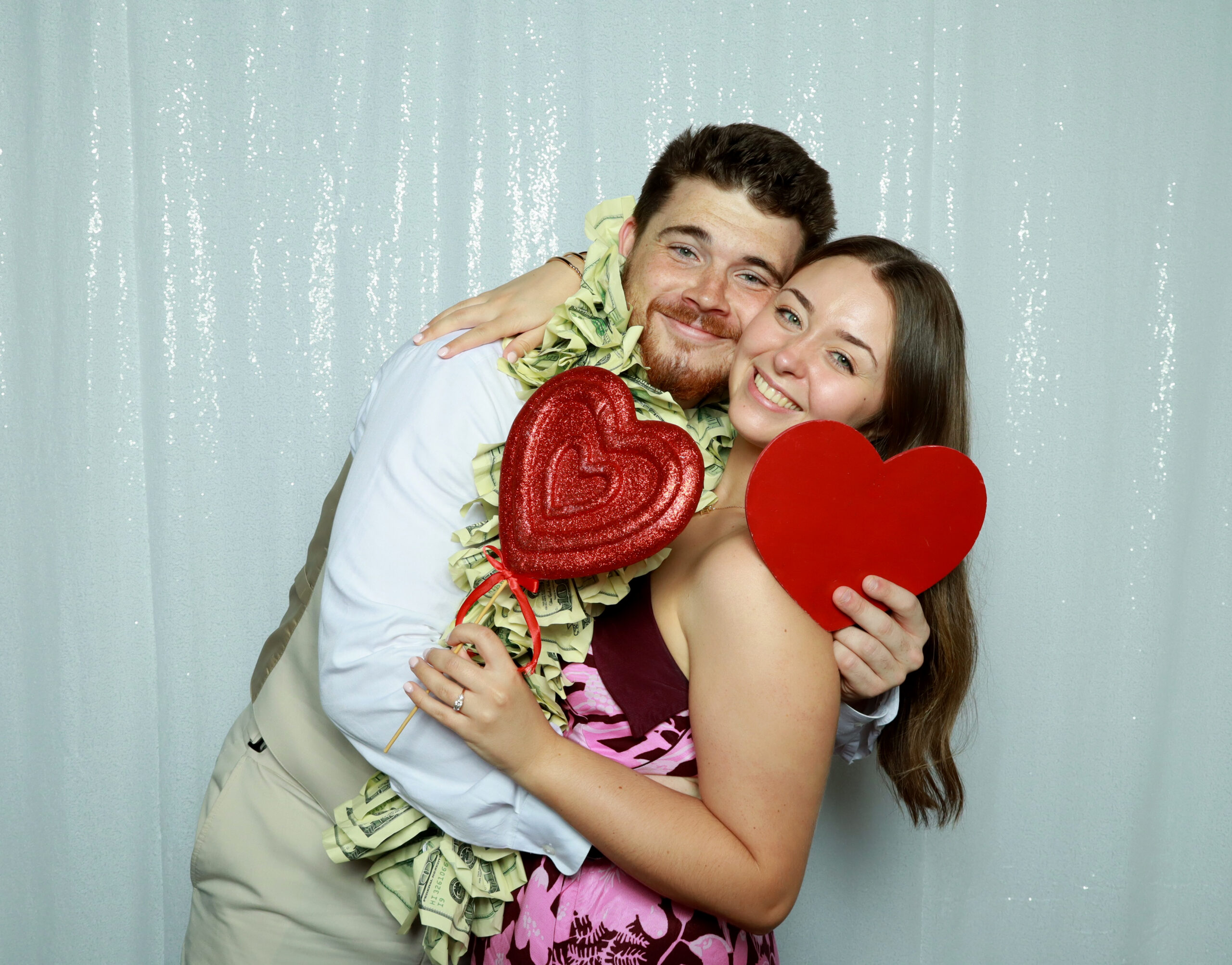 Wedding couple with a money garland photo prop against a white sequin backdrop
