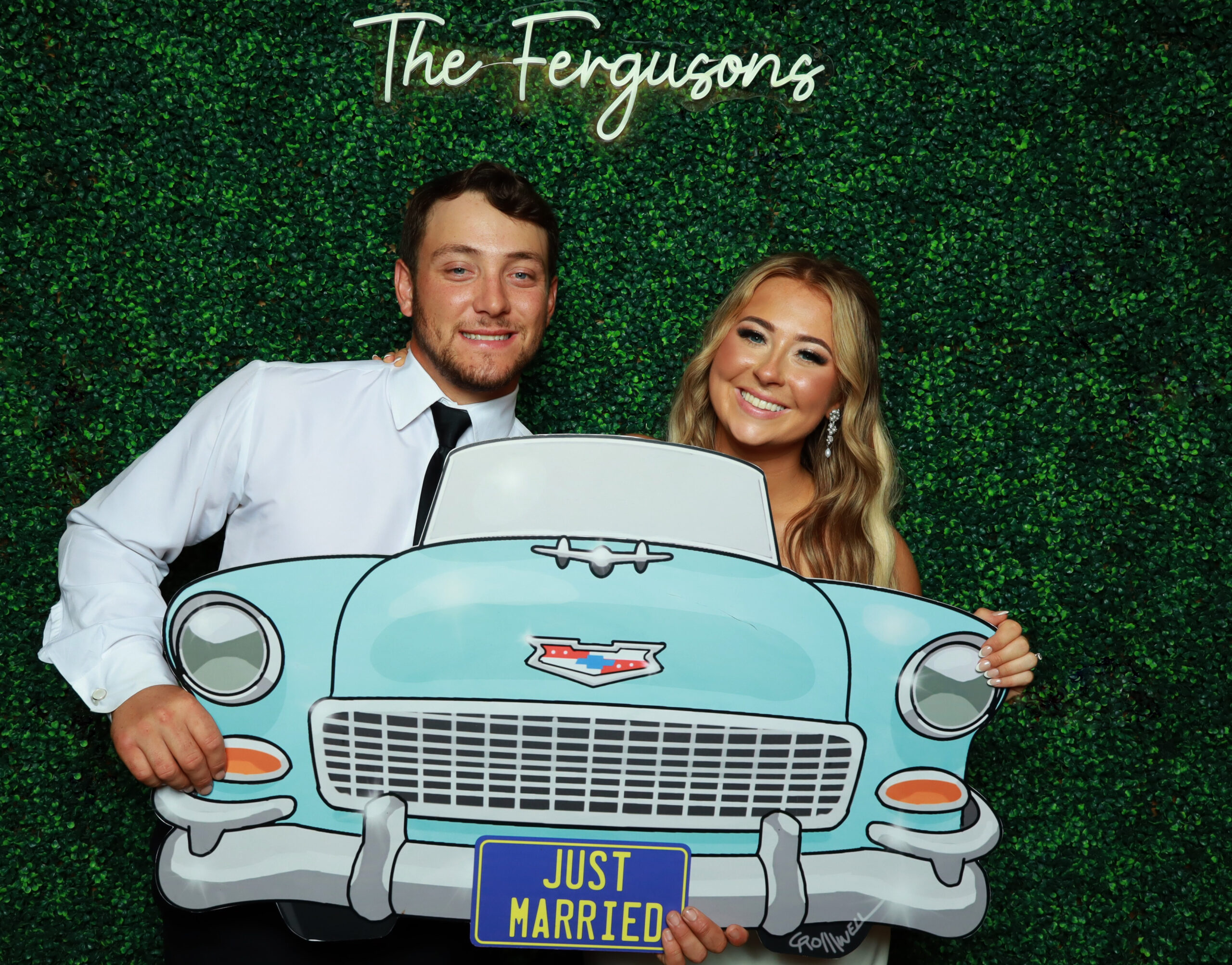 Couple posing with a vintage car photo prop at their wedding