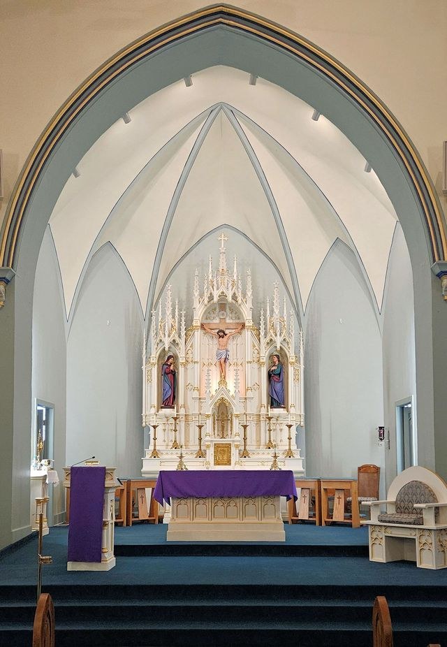 Traditional Catholic altar prepared for Mass beneath a carved Gothic reredos