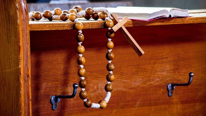 Wooden rosary draped over a church pew