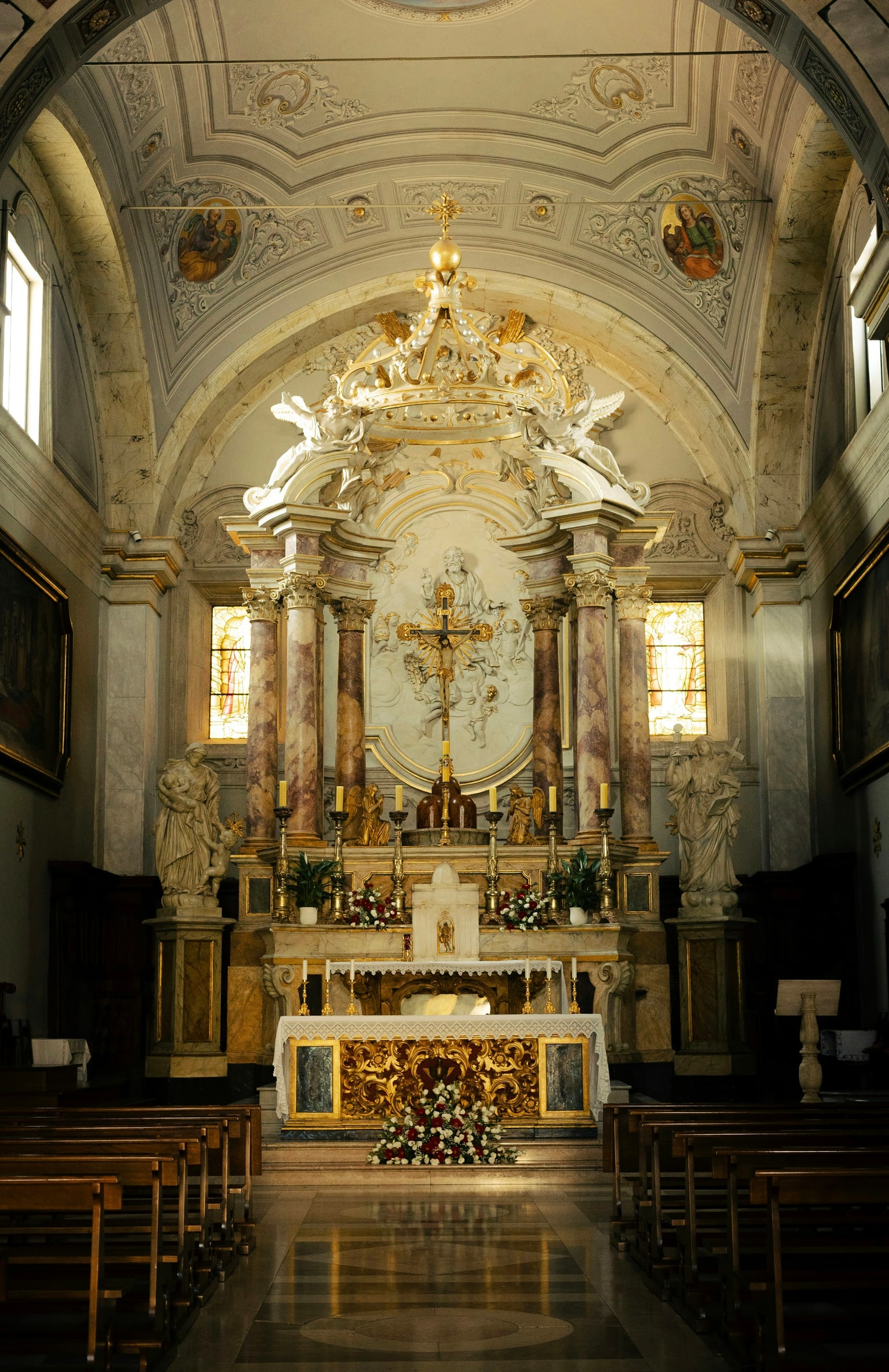 Catholic altar framed by marble columns and stained-glass windows