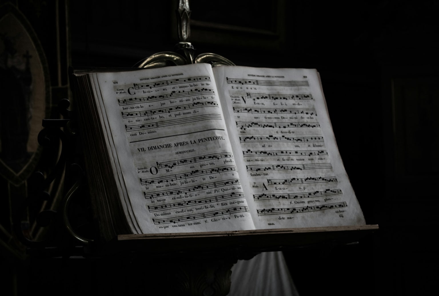 Open Gregorian chant book on a stand in a dark chapel