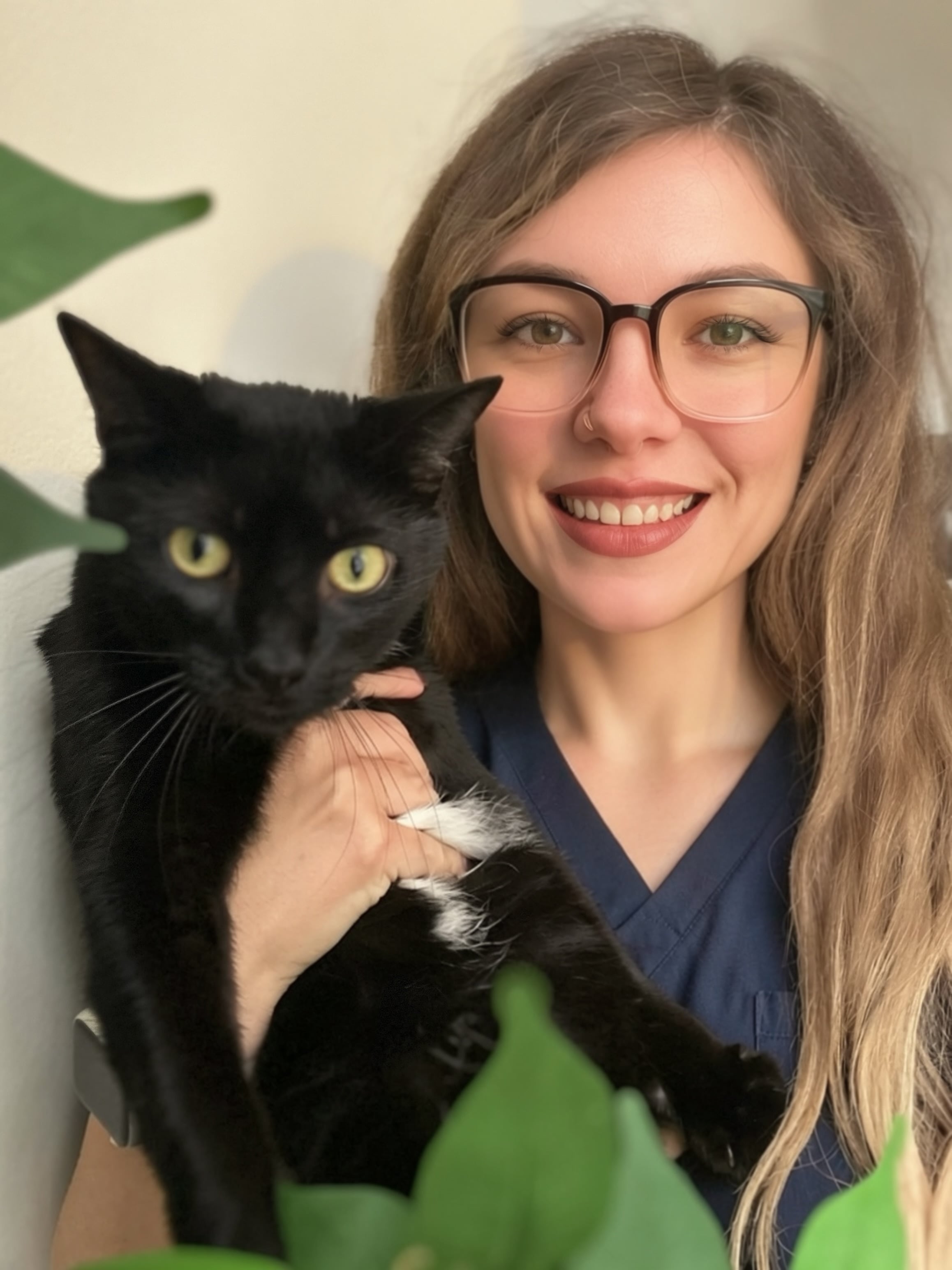 Jordana in blue scrubs holding a black cat