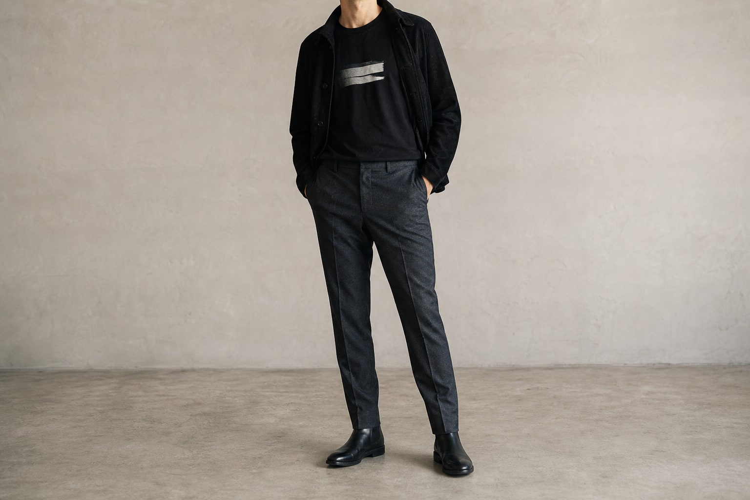 Black graphic T-shirt paired with charcoal trousers, a jacket, and boots