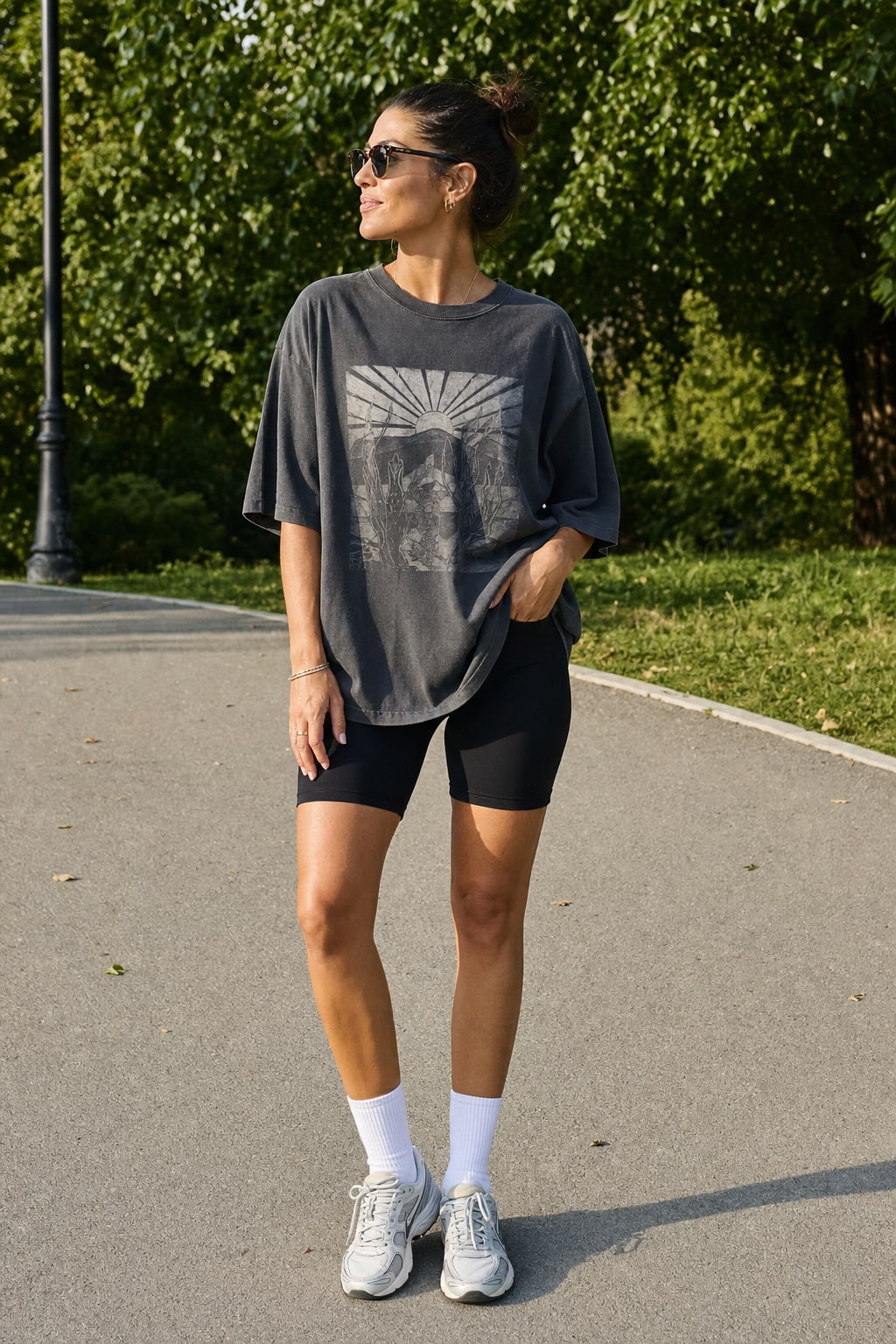Woman wearing an oversized charcoal graphic T-shirt with black bike shorts and sneakers