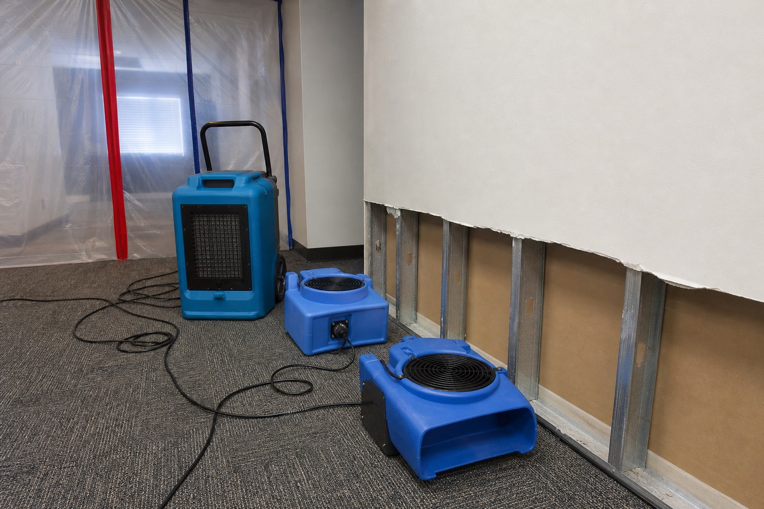 Drying equipment beside an affected wall in a managed property