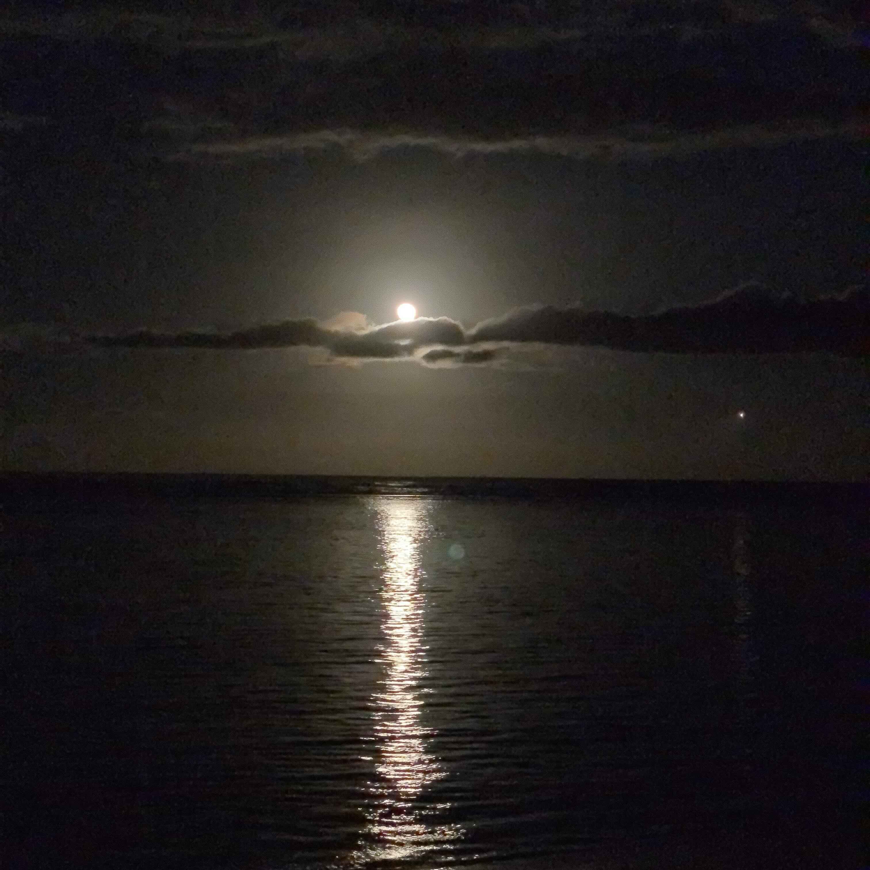 A full moon rising over the ocean