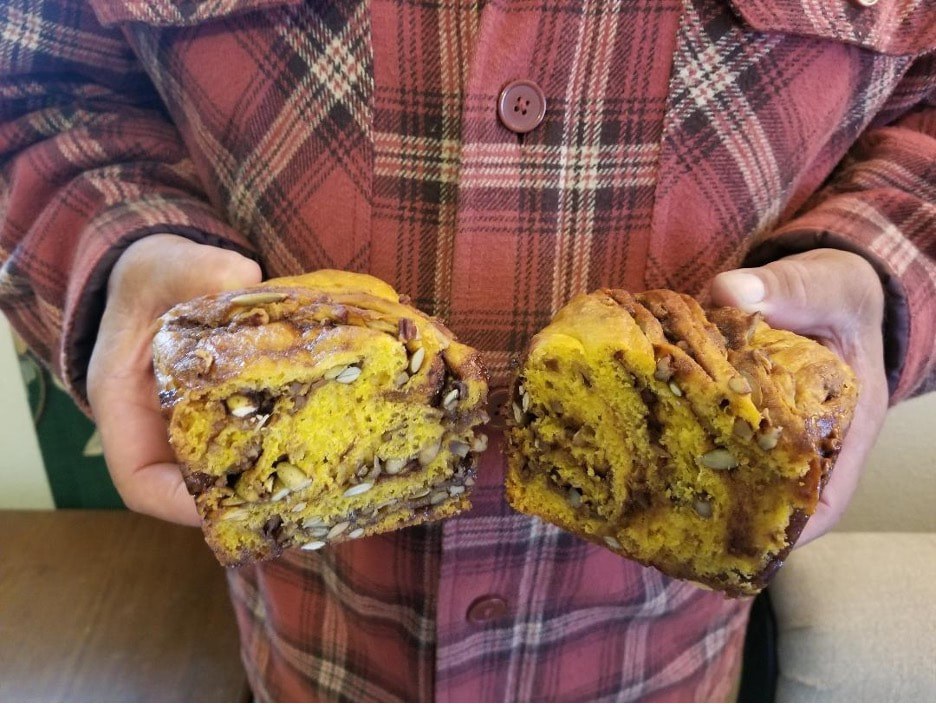 Person holding a sliced loaf of cinnamon swirl bread.