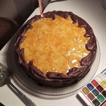 A round cake with chocolate frosting and caramelized topping.