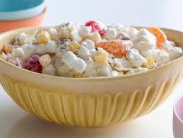 A bowl of creamy fruit salad with marshmallows and assorted fruits.