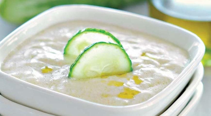 Creamy soup garnished with cucumber slices in a white bowl.