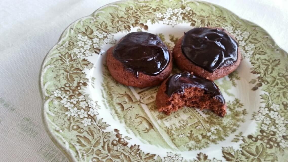 Chocolate-covered cookies on a decorative plate, one with a bite taken.