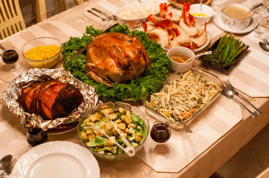 A festive table with roasted chicken, shrimp, salad, and sides.