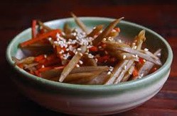 A bowl of cooked burdock root garnished with sesame seeds.