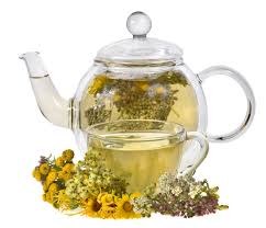 Glass teapot with herbal tea and flowers.