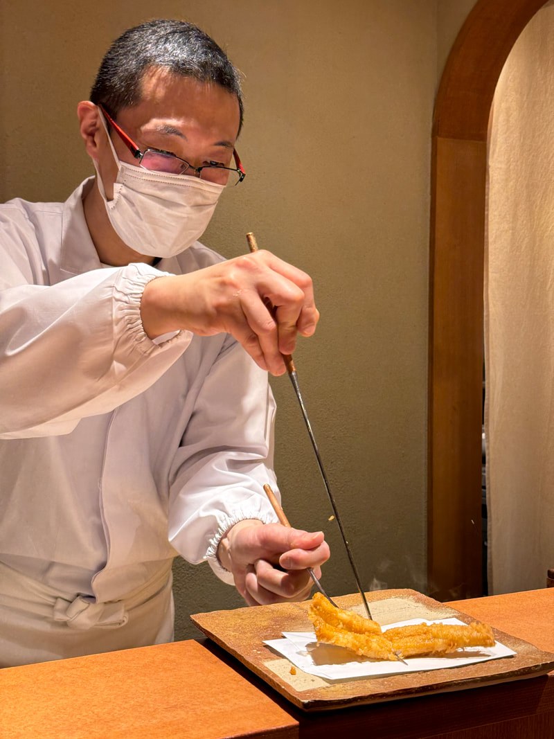 Chef expertly preparing sushi with precision and care.